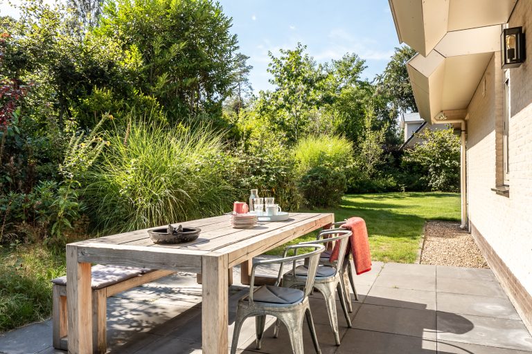 Zijtuin met eettafel vrijstaand vakantiehuis Epe zonnig zijterras